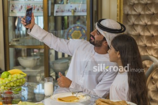 Middle Eastern man taking a picture with the young girl|