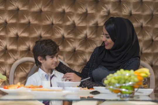Arab mother sitting with her son during breakfast|-