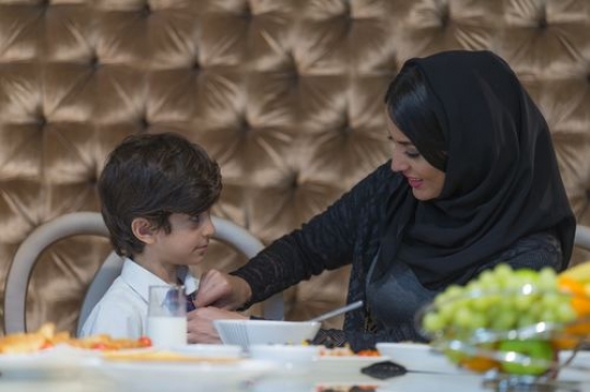 Middle eastern mother helping her son with his tie|-