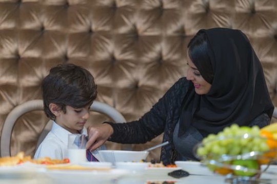 Arab mother helping her son with tie|-