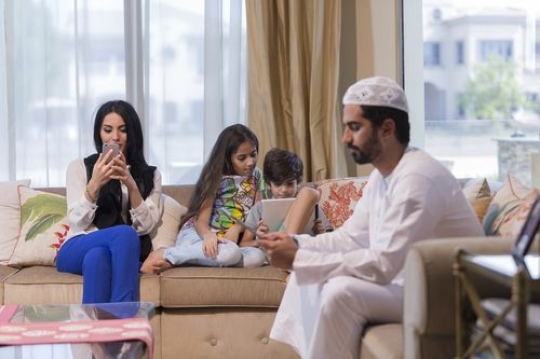Arab family sitting all together on their devices|-