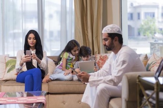 Arab family sitting all together on their devices|-