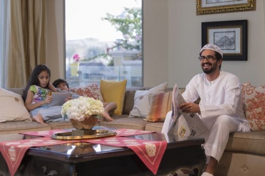 Arab man smiling and the kids on their devices|-