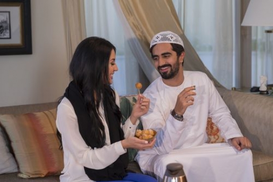 Arab father and mother sitting together having arabic sweets|-