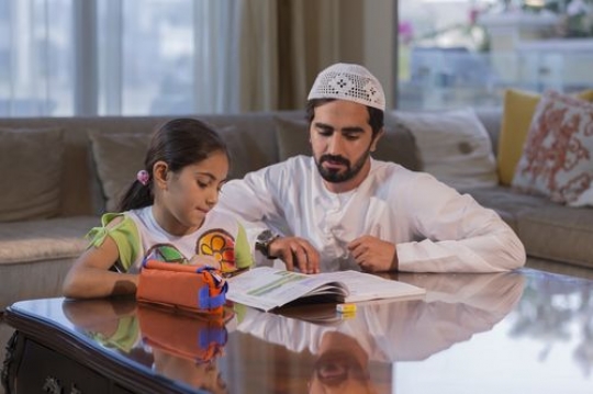 Arabian father helping his daughter with her homework |-