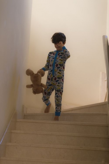 Arabian kid dressed in his pajamas walking down the stairs |-