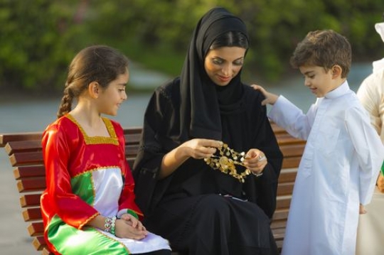 Family dressed in traditional attire sitting on the bench|-