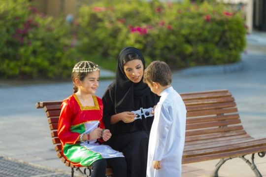 Mother and siblings sitting on the bench talking to each other|-