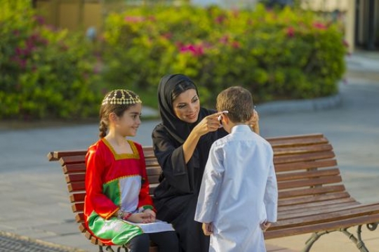 Mother and her kids sitting on the bench celebrating national day|-