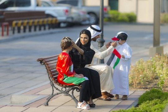 Arab Family celebrating national day while sitting on the bench|-