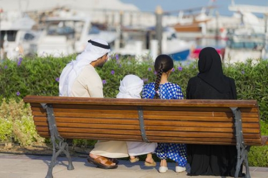 Arab family sitting on the bench spending time together|-