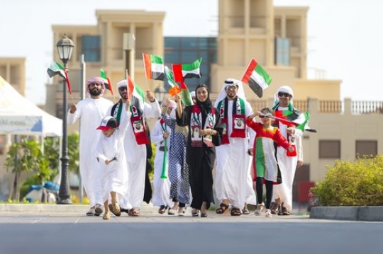UAE Nationals walking with UAE Flags during a National Day Parade|
