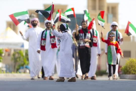 Arab family carrying UAE Flags during the National Day parade|
