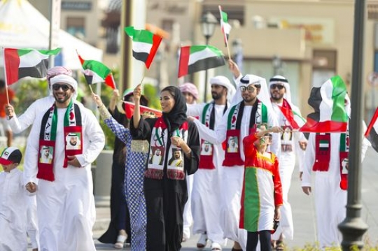 Family and kids carrying UAE Flags during a National Day Parade|