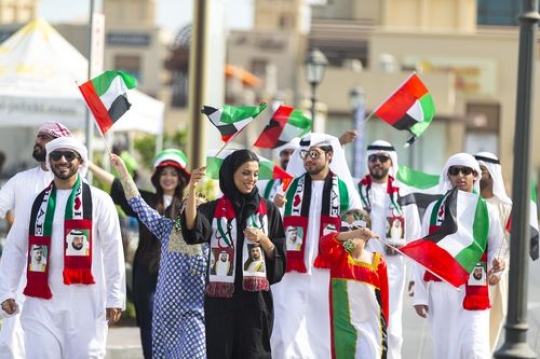 Arab family and kids carrying the UAE flags during a National Day Parade|