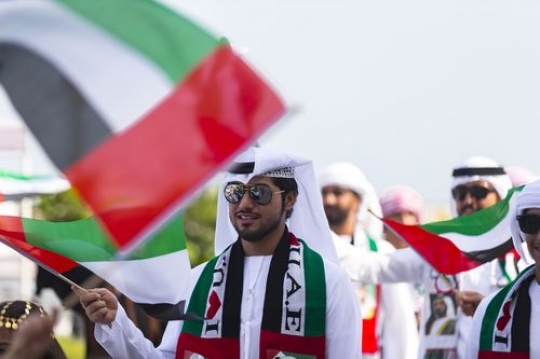 Arab man with a group of people representing their country during a National Day parade|