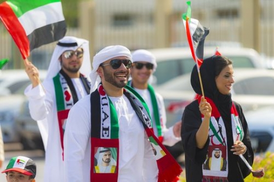 Arab man and woman at a parade celebrating National Day|