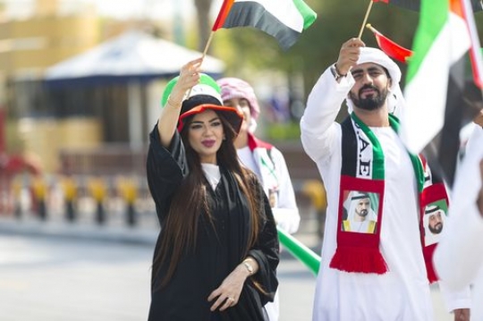Arab man and woman dressed in the UAE traditional attire celebrating National Day|