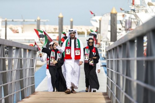 A group of men and women dressed in the traditional UAE attire celebrating National Day|