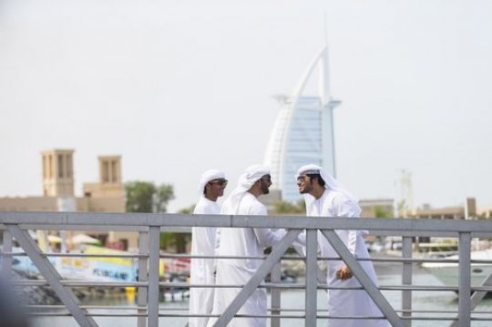 Arab men dressed in the traditional attire greeting each other in the UAE traditional way|
