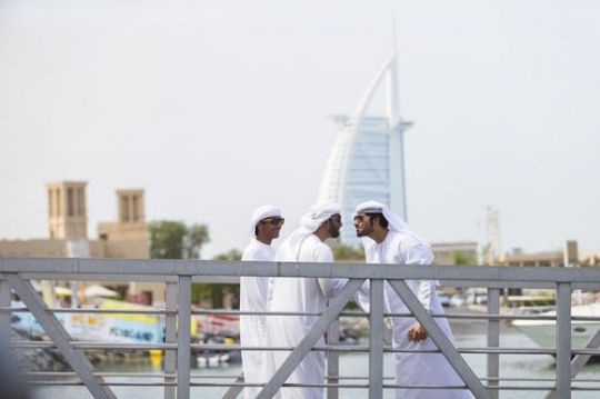 Men standing by the dock greeting each other in the UAE traditional way|