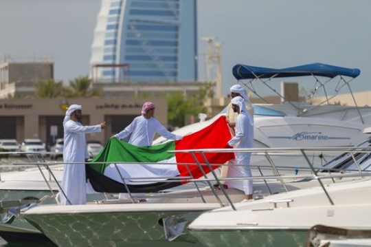 Arab men holding the UAE flag to celebrate National Day|