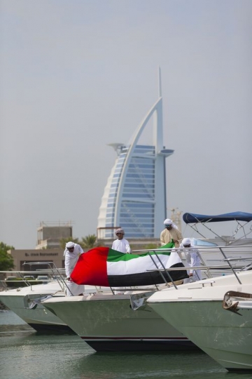Arab men attaching the UAE Flag to the Yacht to celebrate National Day|