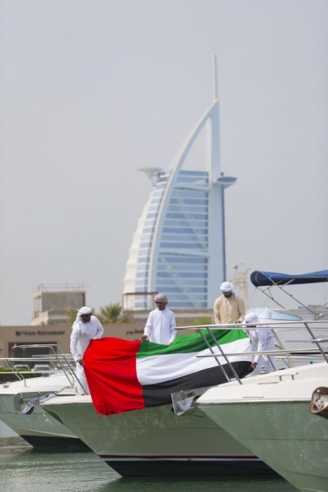 Arab men dressed in the traditional UAE attire celebrating National Day on a Yacht|
