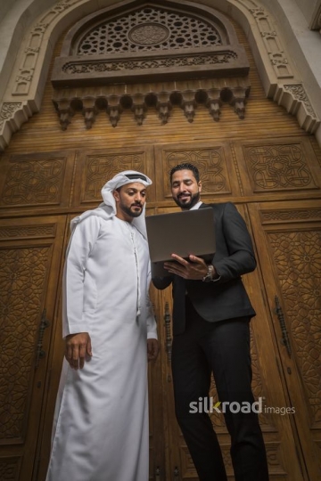 Businessmen standing next to each other using the laptop|-