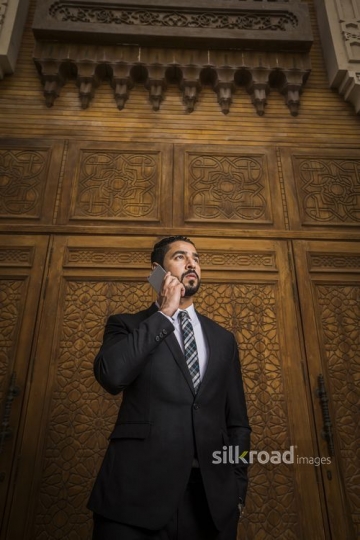 Middle Eastern Businessman standing using his mobile|-