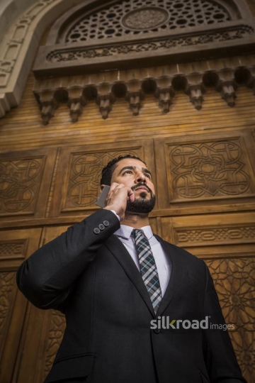 Arab Businessman standing using his mobile|-