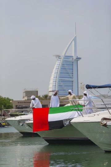 Arab men attaching UAE flag to the Yacht to celebrate National Day|