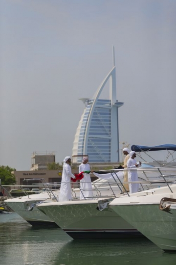 Arab men standing on the yacht holding a UAE Flag preparing for National Day|