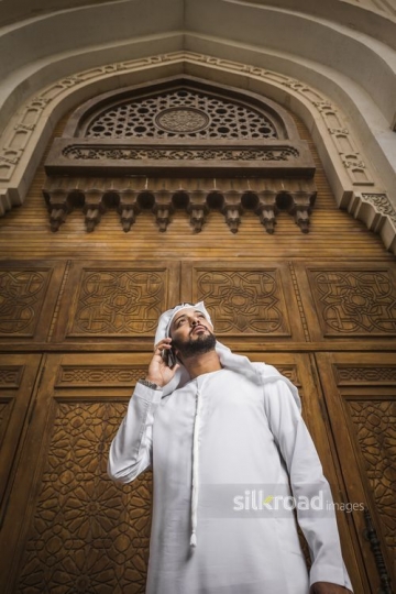 Arab Businessman standing using his mobile|-