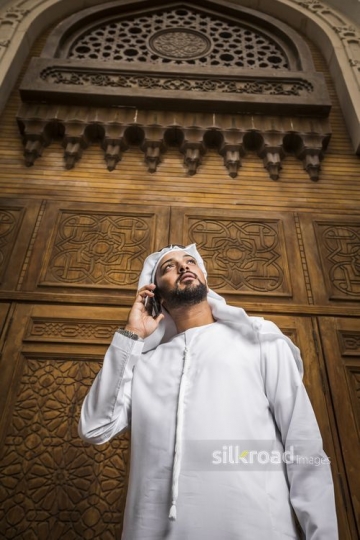 Middle Eastern Businessman standing using his mobile|-
