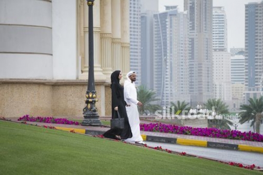Middle Eastern business man and business woman walking alongside each other|-