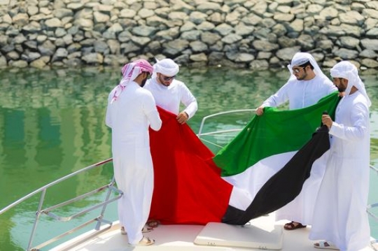 Arabian men standing on the yacht celebrating National Day|