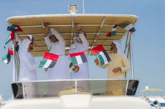 Arabian men dressed in the traditional attire decorating the Yacht for the UAE National Day|