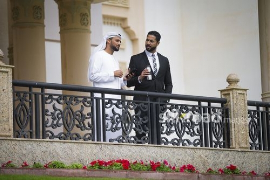 Businessmen standing on the bridge talking to each other|-