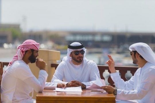 Arab business men dressed in the traditional UAE attire during a meeting|