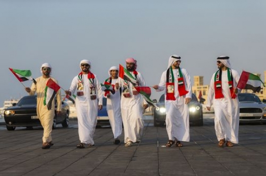Emirati men followed by luxury cars in motion during a National Day Parade|-