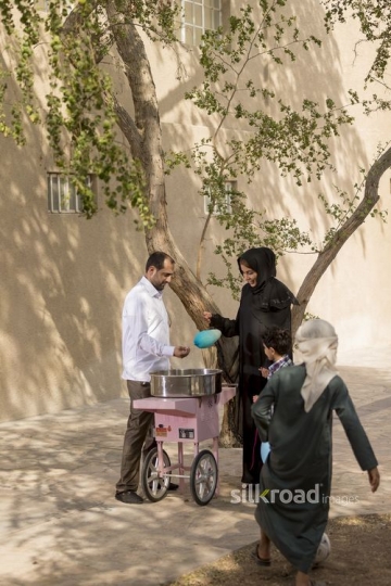 Arab man offering cotton candy to the kid|-