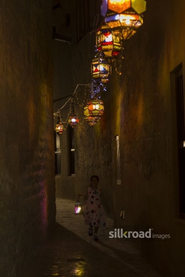 Arab girl running through the pathway decorated by Ramadan Lanterns|-