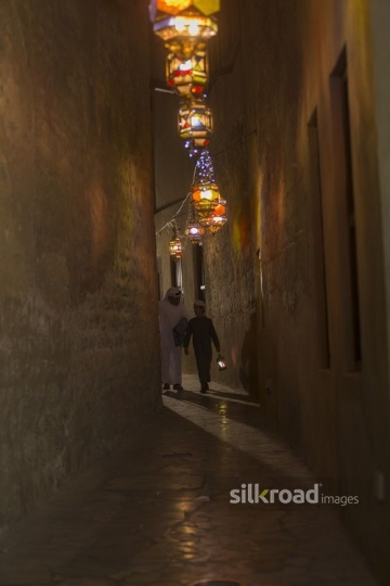 Arab father and son walking together carrying a Ramadan Lantern|-