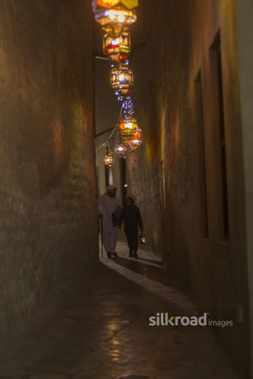 Arab father and son walking through the pathway decorated by Ramadan Lanterns|-