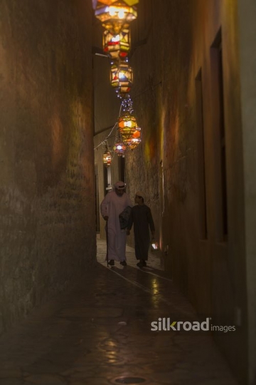Arab father and son walking through the pathway decorated by Ramadan Lanterns|-