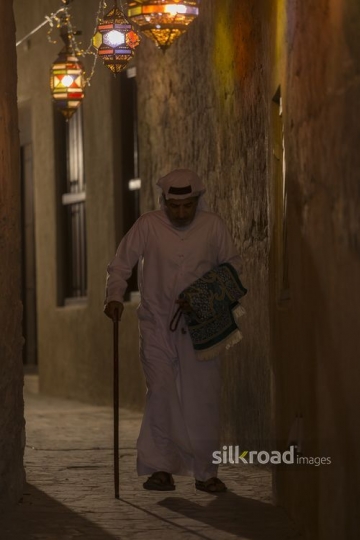 Middle Eastern man walking through the alleyway decorated with Ramadan Lanterns |-