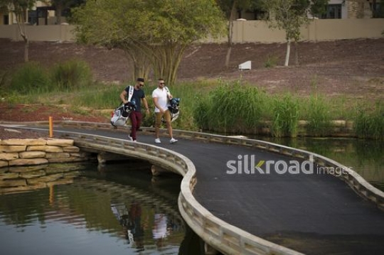 Middle Eastern men walking together carrying Golf bags|-