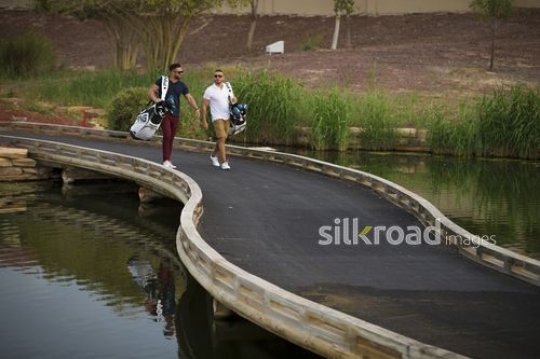 Young Middle Eastern men carrying Golf bags walking together|-