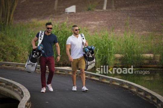 Young Middle Eastern men walking together carrying Golf bags|-